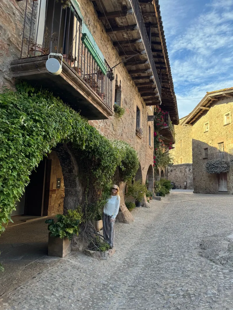 My mom standing behind an old house with arches in Santa Pau