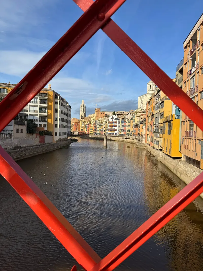 View of Girona's riverside houses framed by the red iron bridge